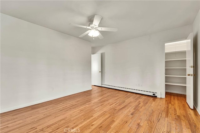 unfurnished room featuring baseboard heating, a ceiling fan, and light wood-style floors