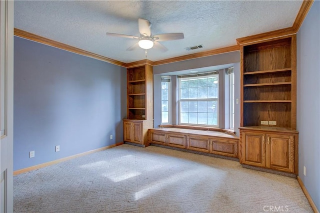 spare room with a textured ceiling, visible vents, a ceiling fan, and crown molding