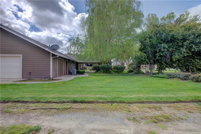 view of yard featuring an attached garage and central AC