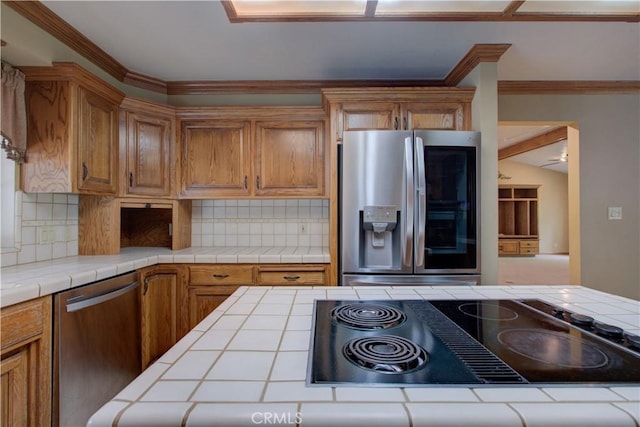 kitchen with backsplash, stainless steel appliances, tile counters, and brown cabinets