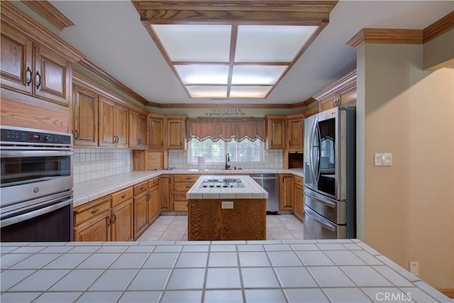kitchen with tasteful backsplash, tile counters, a kitchen island, and appliances with stainless steel finishes