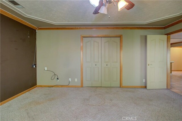 unfurnished bedroom featuring carpet flooring, a textured ceiling, visible vents, a ceiling fan, and a closet