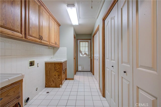 clothes washing area with light tile patterned floors, a sink, cabinet space, and hookup for a washing machine