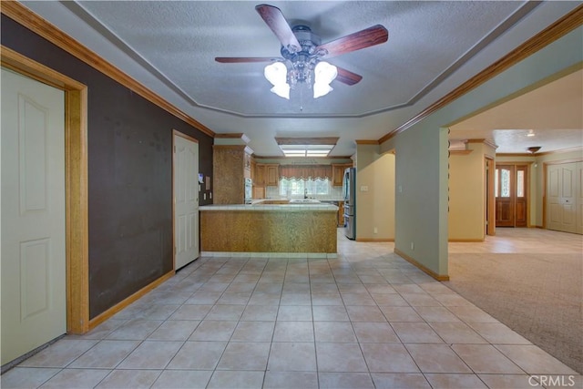 kitchen with open floor plan, ornamental molding, freestanding refrigerator, a ceiling fan, and a peninsula