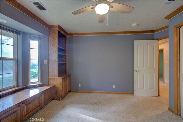 unfurnished room featuring a textured ceiling, visible vents, crown molding, and light carpet