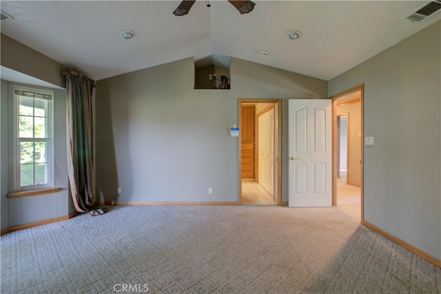 carpeted spare room with vaulted ceiling, baseboards, ceiling fan, and visible vents