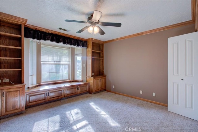 unfurnished room with crown molding, baseboards, a textured ceiling, visible vents, and a ceiling fan