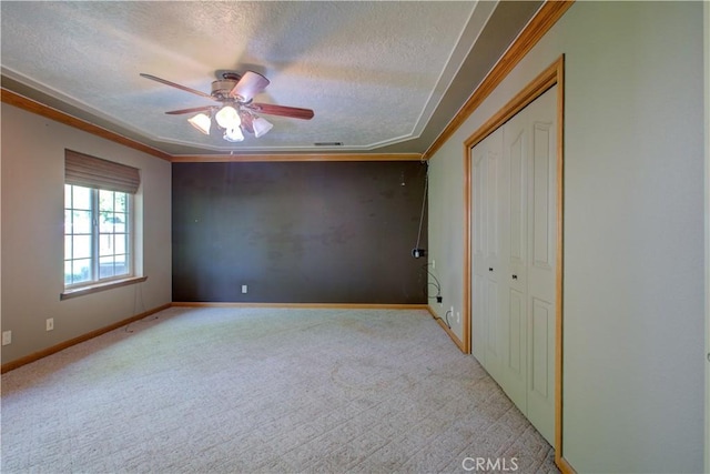 unfurnished bedroom featuring ornamental molding, baseboards, a textured ceiling, light carpet, and a closet