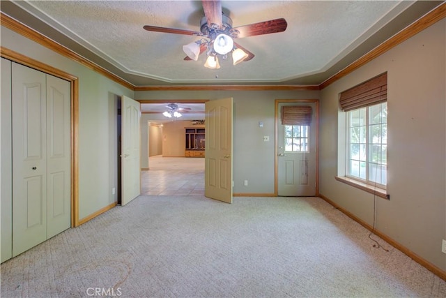 carpeted spare room with baseboards, a textured ceiling, a ceiling fan, and ornamental molding