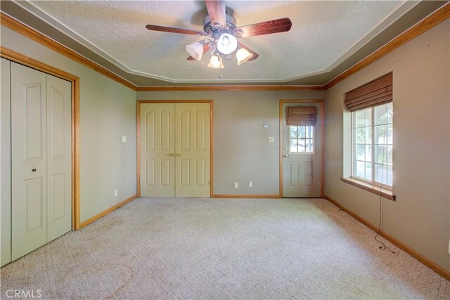 unfurnished bedroom with baseboards, carpet flooring, a textured ceiling, and crown molding