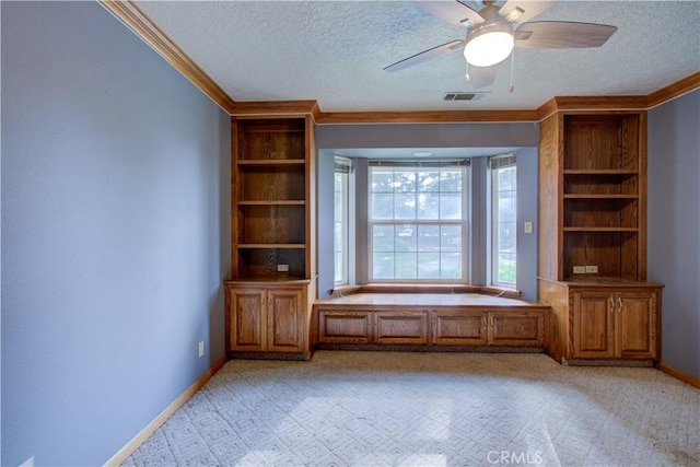 interior space featuring ornamental molding, baseboards, a textured ceiling, visible vents, and a ceiling fan