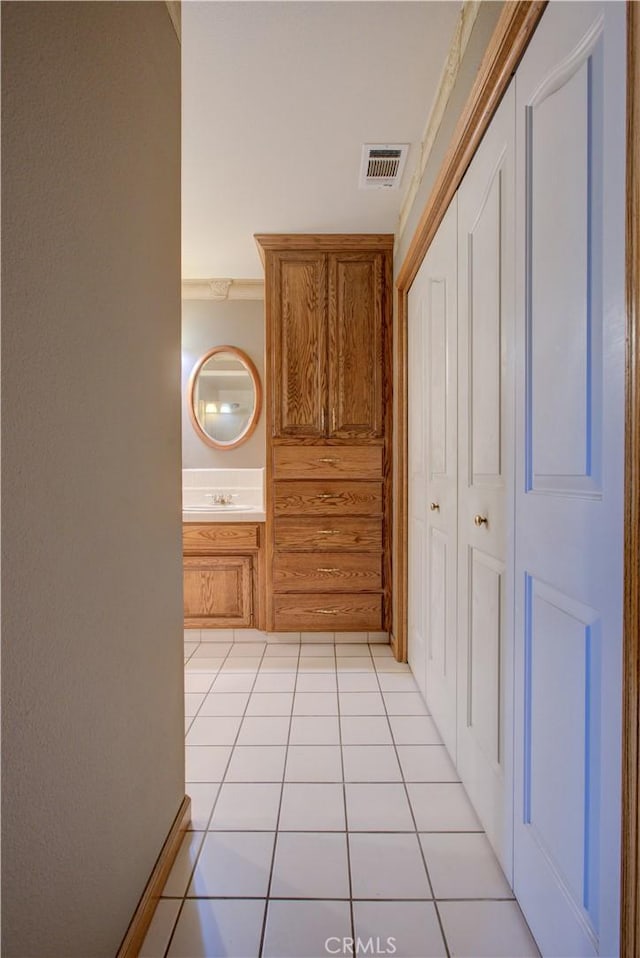 hallway with a sink, visible vents, and light tile patterned floors