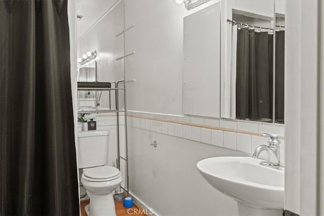 bathroom with toilet, wood finished floors, and a sink