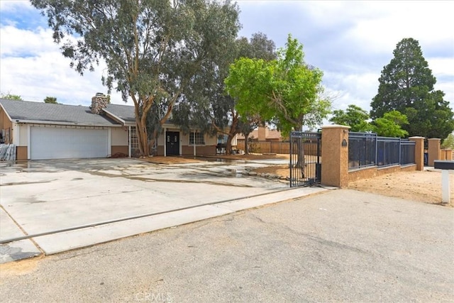 view of front facade featuring concrete driveway, a garage, fence, and a gate