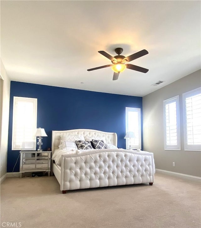 carpeted bedroom with ceiling fan, baseboards, and visible vents