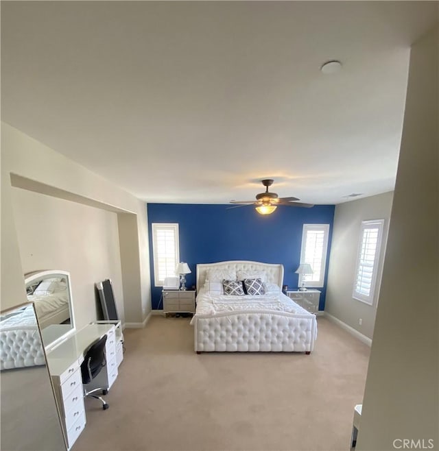 bedroom with light carpet, multiple windows, and baseboards