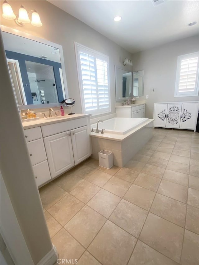 bathroom with tile patterned flooring, a sink, a walk in shower, two vanities, and a garden tub