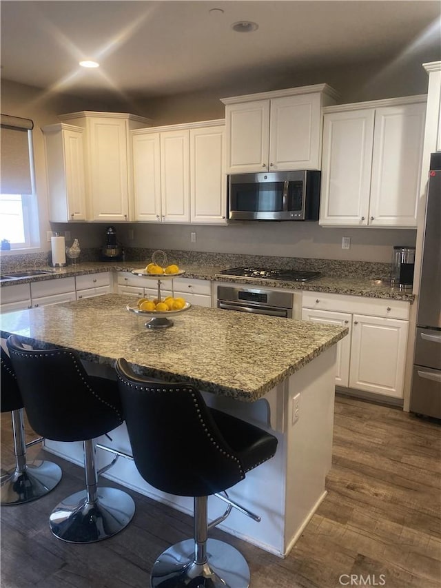 kitchen featuring a center island, white cabinetry, appliances with stainless steel finishes, and a kitchen breakfast bar