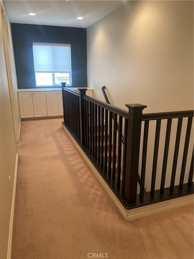 hall featuring light carpet, recessed lighting, and an upstairs landing