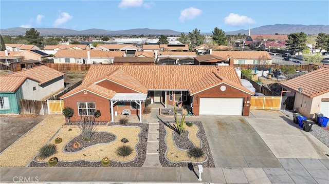 view of front facade featuring a residential view, driveway, fence, and a mountain view