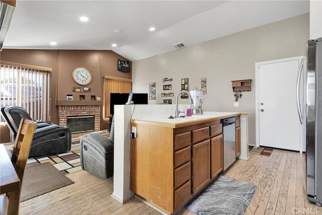 kitchen with light wood-style flooring, a sink, stainless steel appliances, and lofted ceiling