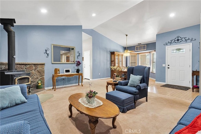 living room featuring baseboards, lofted ceiling, a wood stove, and recessed lighting