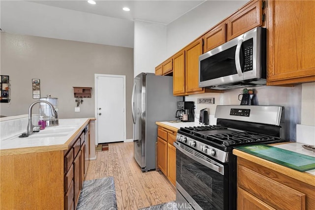 kitchen featuring light countertops, a sink, appliances with stainless steel finishes, brown cabinets, and light wood-style flooring