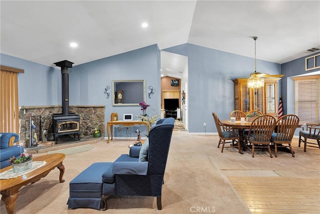 carpeted living area featuring visible vents, baseboards, recessed lighting, lofted ceiling, and a wood stove
