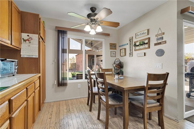 dining room featuring baseboards, light wood-style floors, and ceiling fan