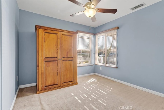 unfurnished bedroom featuring light carpet, baseboards, ceiling fan, and visible vents