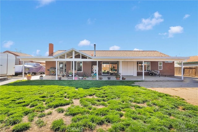 rear view of property with fence, stucco siding, a patio area, and a yard
