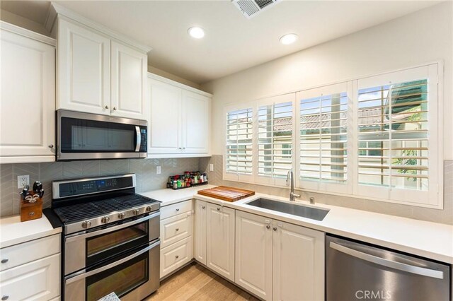 133 Lantana Dr, Stanton, CA 90680 - kitchen with appliances with stainless steel finishes, light countertops, tasteful backsplash, white cabinetry, and recessed lighting
