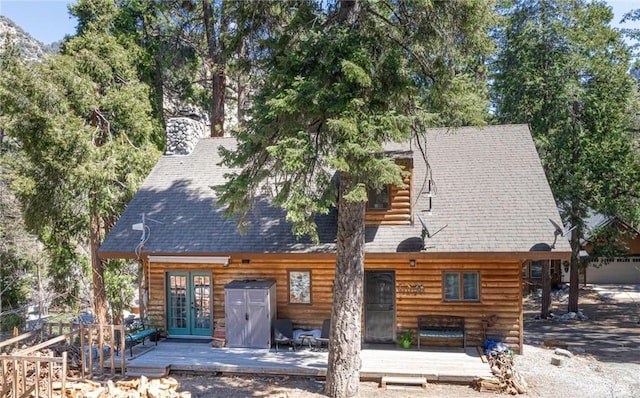 back of house with french doors, roof with shingles, faux log siding, and a deck