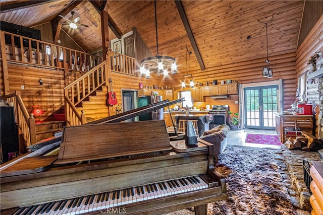 interior space with rustic walls, ceiling fan with notable chandelier, stairway, wooden ceiling, and high vaulted ceiling