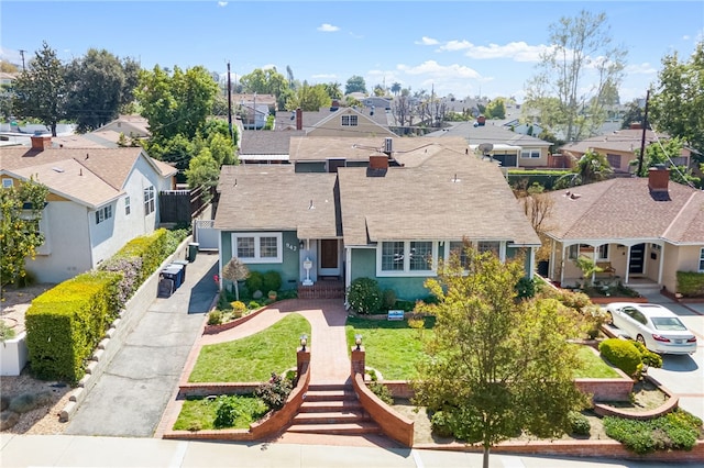 view of front facade with stucco siding, a shingled roof, a front yard, and a residential view