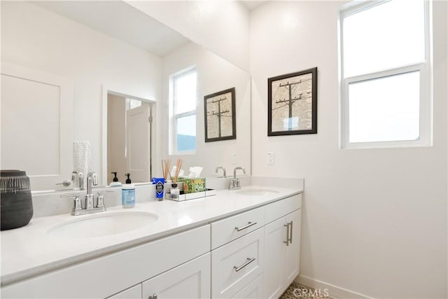 bathroom with double vanity, a sink, and baseboards