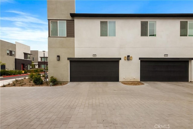 view of front of property featuring stucco siding, decorative driveway, and a garage