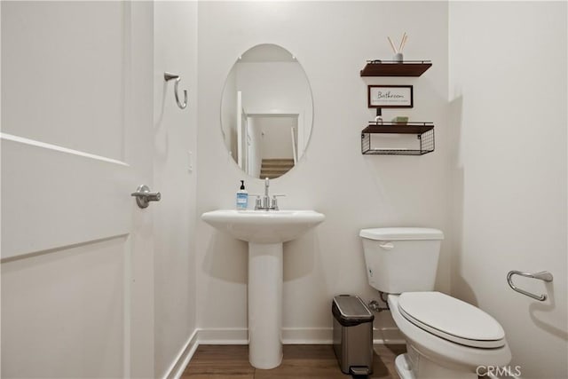 bathroom with baseboards, toilet, and wood finished floors