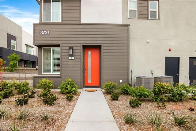 property entrance with central AC and stucco siding
