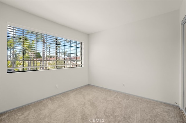 carpeted spare room with plenty of natural light and baseboards