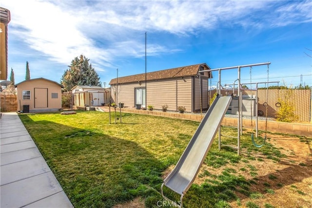 view of yard featuring a storage shed, a playground, fence, and an outdoor structure