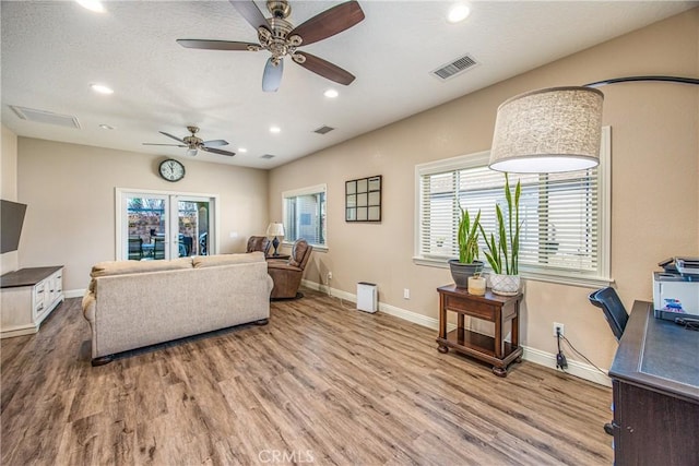 living area featuring wood finished floors, a ceiling fan, visible vents, and recessed lighting