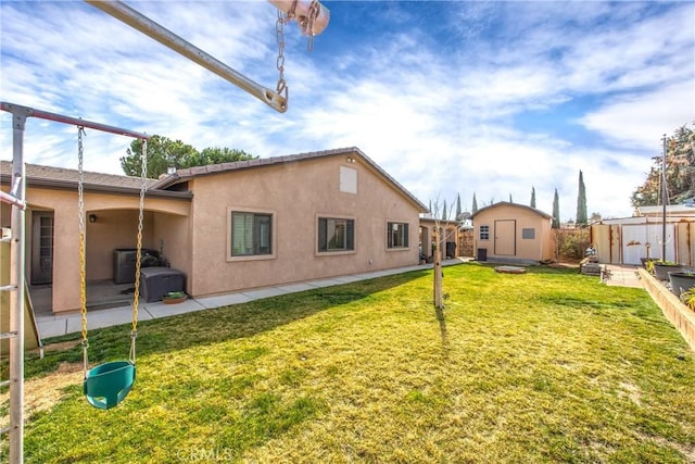 rear view of property featuring a storage shed, a patio area, a yard, an outdoor structure, and stucco siding