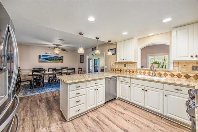 kitchen featuring a sink, ceiling fan, light wood-type flooring, appliances with stainless steel finishes, and a peninsula
