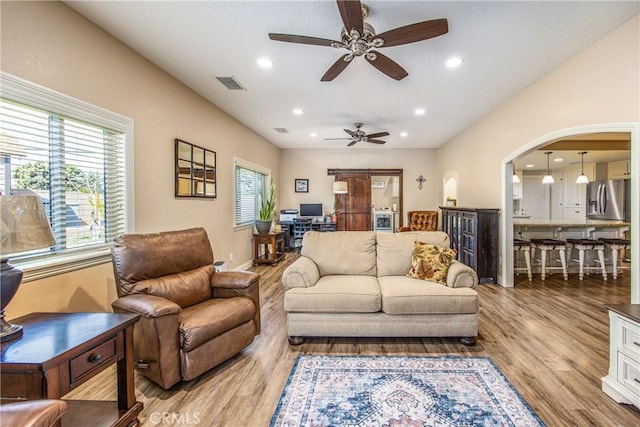 living room with visible vents, ceiling fan, arched walkways, and plenty of natural light