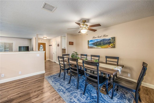 dining space featuring visible vents, baseboards, a ceiling fan, and wood finished floors