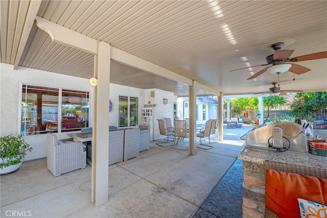 view of patio featuring fence, outdoor dining space, ceiling fan, and an outdoor kitchen
