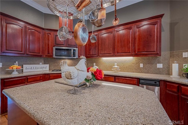 kitchen featuring light stone countertops, stainless steel microwave, reddish brown cabinets, and ornamental molding