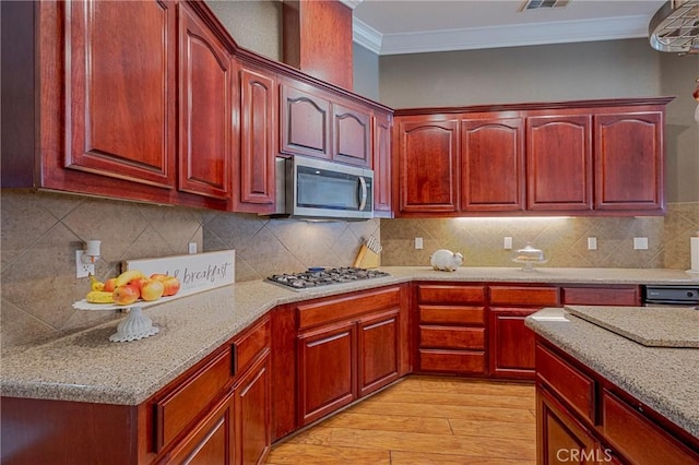 kitchen with reddish brown cabinets, light stone counters, appliances with stainless steel finishes, light wood-type flooring, and crown molding