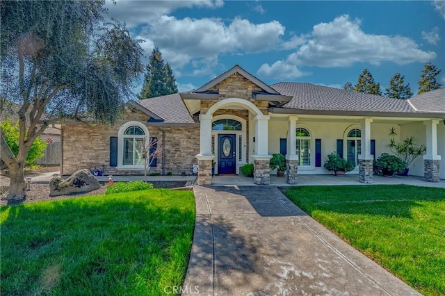 view of front of house with covered porch, stucco siding, a front lawn, and stone siding